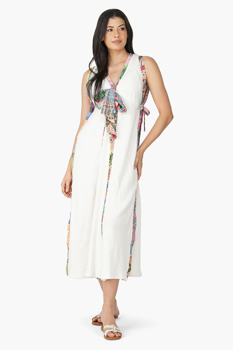 Front view of a sleeveless off-white midi wrap dress with multicolor printed panels and tie-up bow detail at the neckline